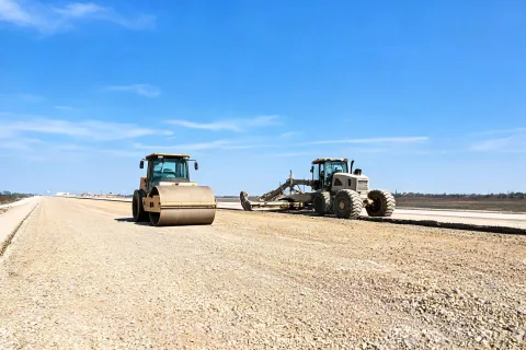 Motor grader and vibratory drum on base course